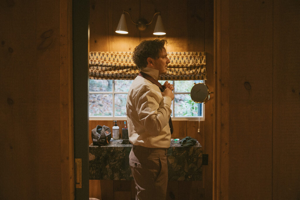 man putting on tie for his elopement