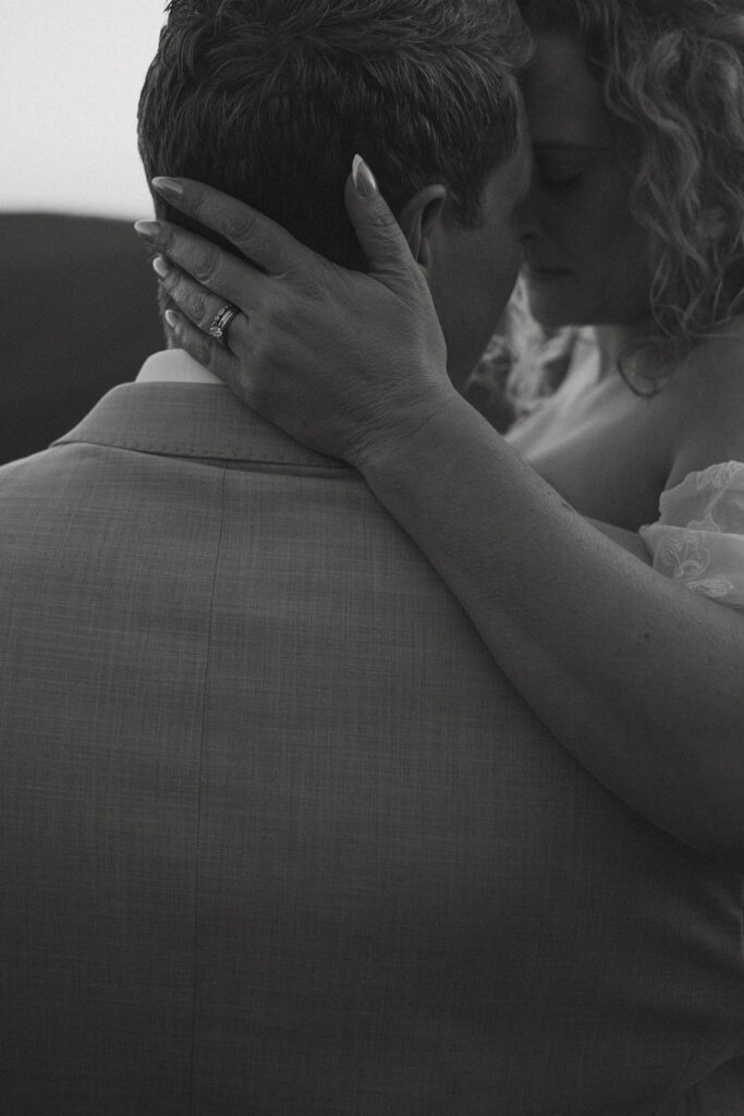 Man and woman in wedding attire standing on rock outcropping overlooking north carolina mountains at sunset