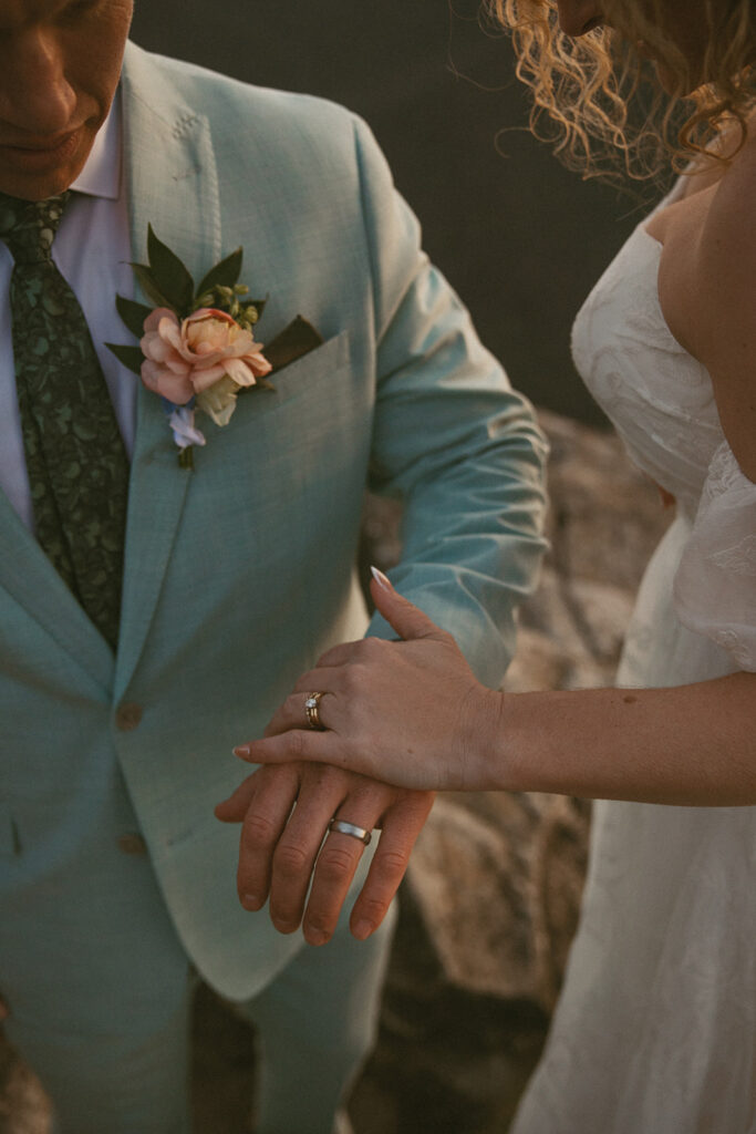 close up of man and womans wedding rings during hiking elopement