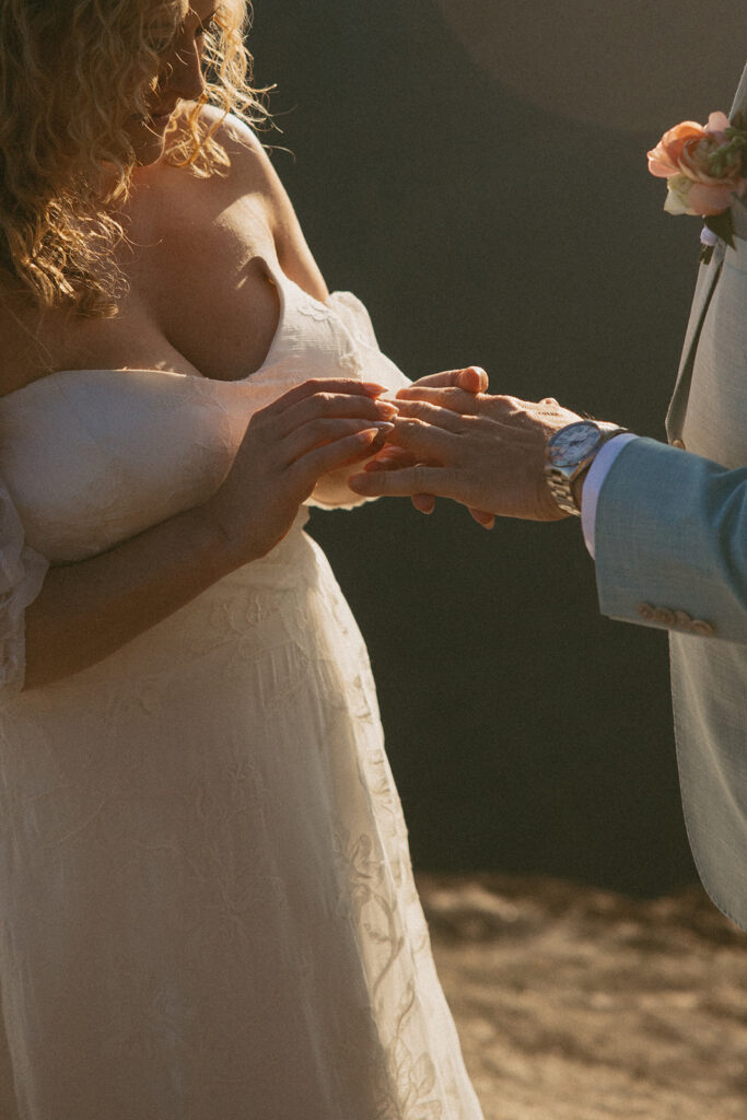 woman putting on man's wedding ring during hiking elopement