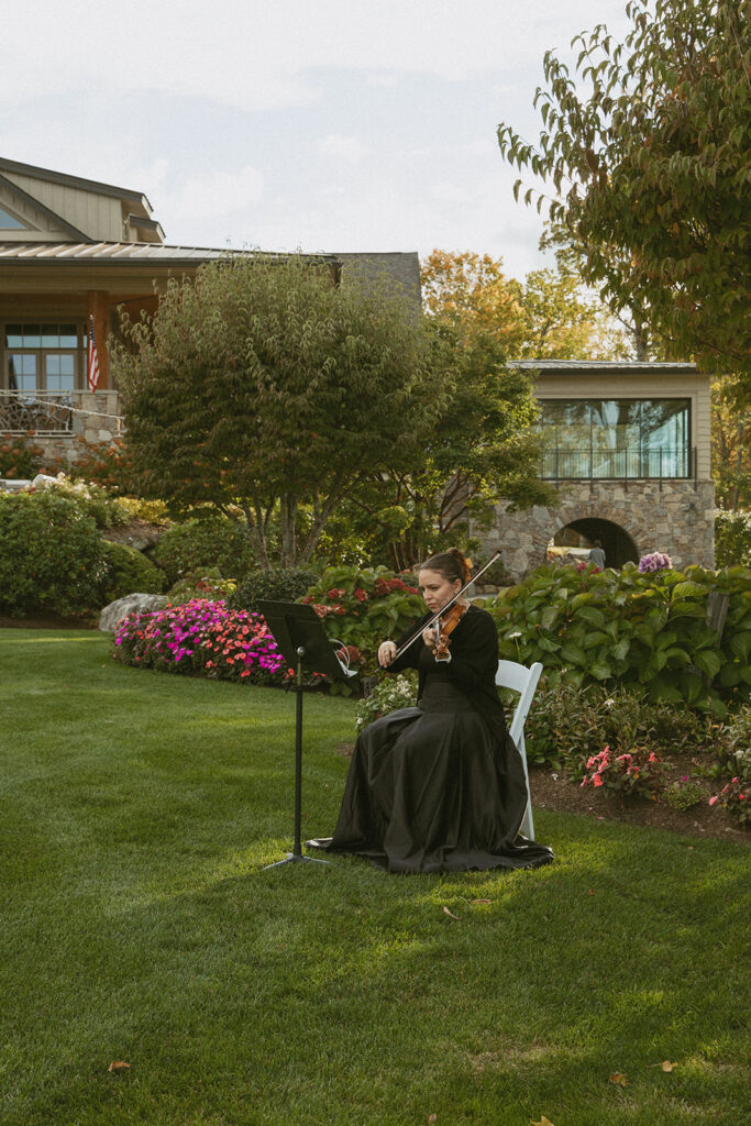 a violinist playing at a wedding in front of trillium links and lake club