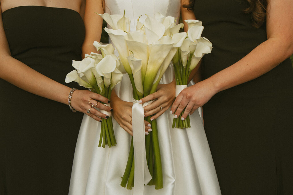 a bride holding her bouquet with her two bridesmaids holding their bouquets beside hers