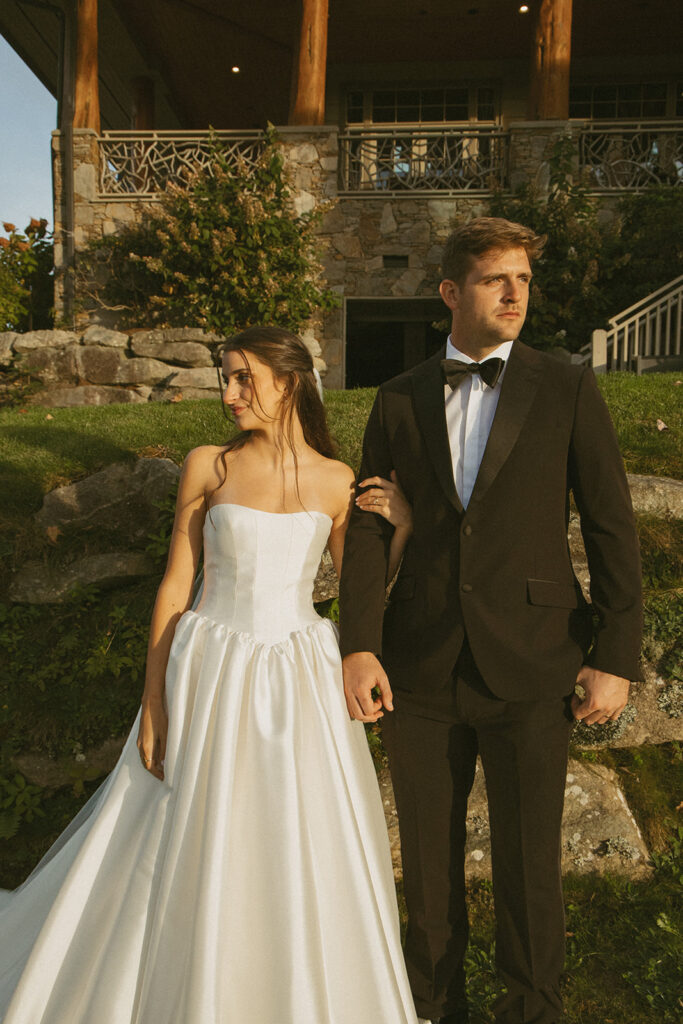 husband and wife with arms linked looking opposite directions