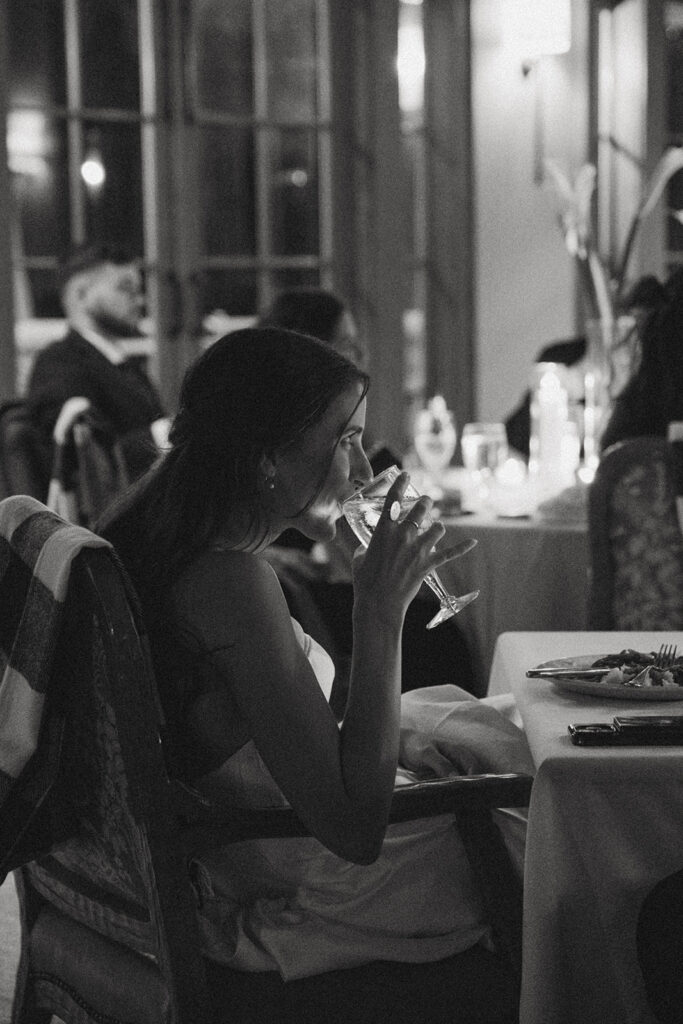 a woman drinking water out of wine glass at her wedding reception