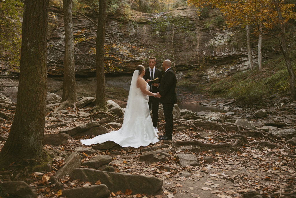 man and woman in wedding attire during ceremony at cherokee falls in cloudland canyon