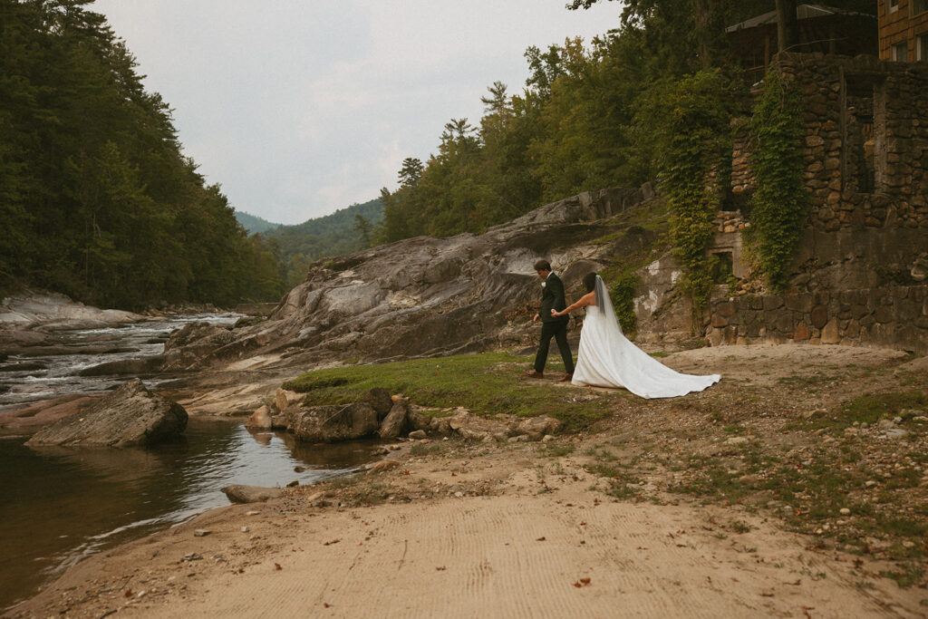 Bride and groom walking towards creek at Brown Mountain Beach Resort in North Carolina.