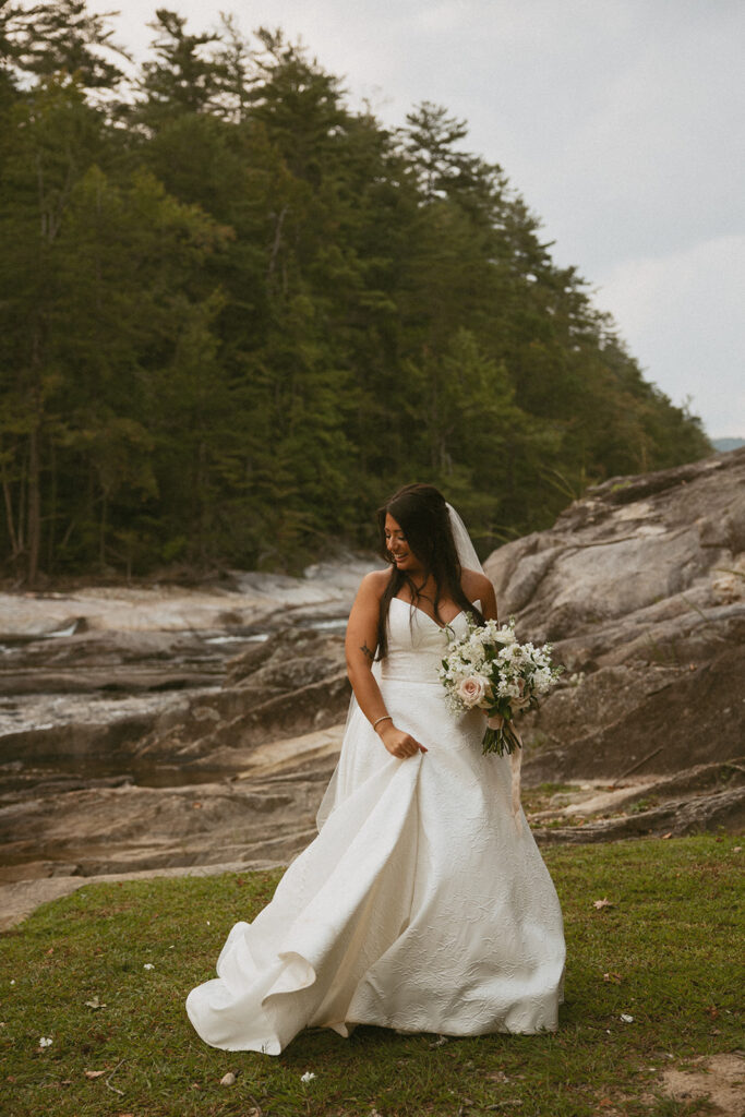 Bride playing with her dress beside the creek at Brown Mountain Beach Resort. 
