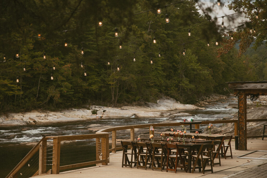 Tables and string lights with wilson creek behind it at Brown Mountain Beach Resort in North Carolina.