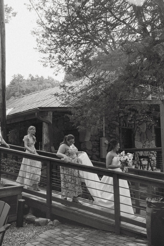 Bridesmaid holding brides dress while they walk down path at Brown mountain Beach Resort.
